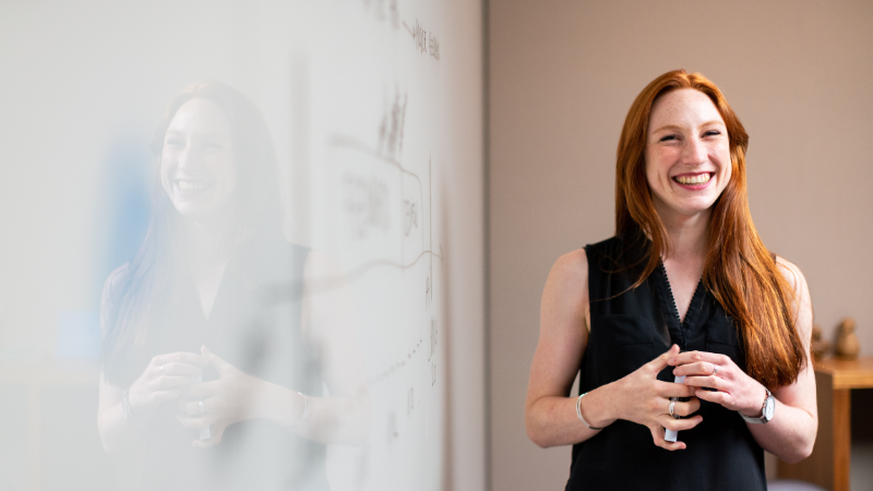 woman standing in front of a whiteboard giving a presentation