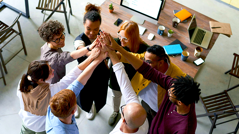team all in on a project with high fives