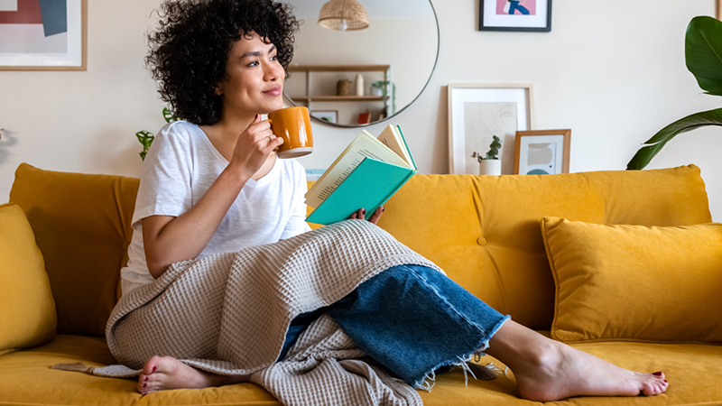 woman enjoying a beverage while relaxing with a book