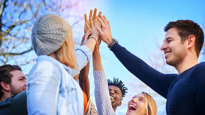 A group of high performers joining hands together in celebration